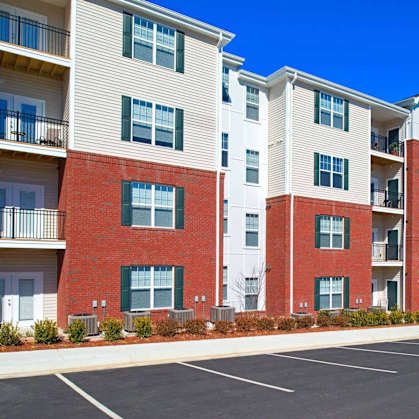 A row of apartment buildings with a car parked in the parking lot.