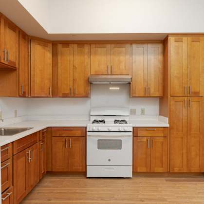 an empty kitchen with wooden cabinets and white appliances