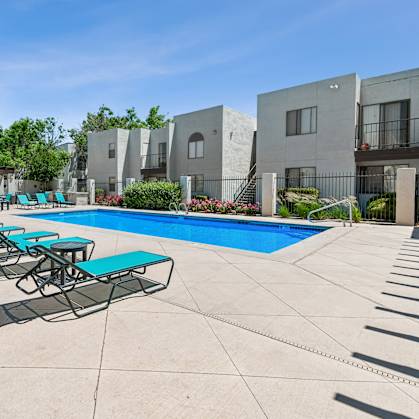A swimming pool surrounded by lounge chairs and buildings.