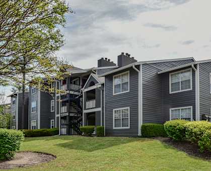A grey apartment building with a tree in front.