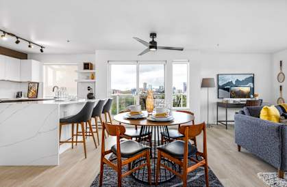 a dining area with a round dining table and four chairs and a kitchen with a breakfast bar