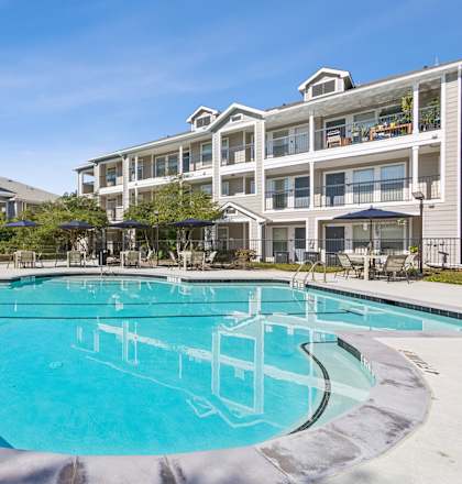 A large swimming pool in front of apartment buildings.