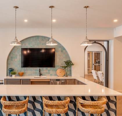 A kitchen with a bar area and a television mounted on the wall.at Corban Freedom Apartments, Orlando Florida