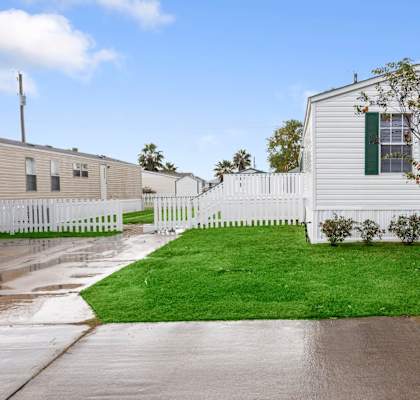 a white house with green shutters and a white picket fence