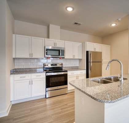 A kitchen with white cabinets and a granite countertop.