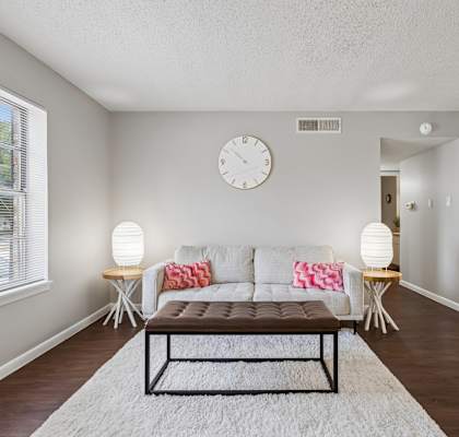 A living room with a couch, a table, and a clock on the wall.