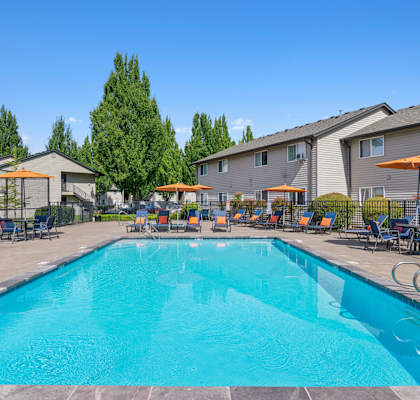 A swimming pool surrounded by chairs and umbrellas in a sunny day.