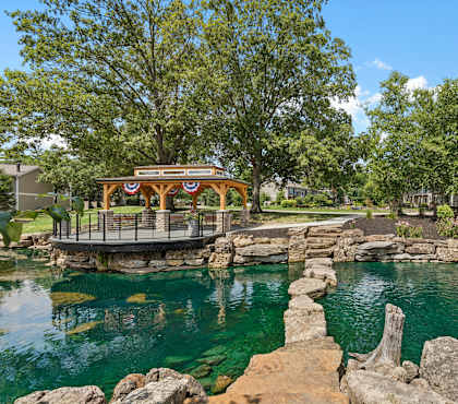 A gazebo sits on a rocky outcrop over a body of water.