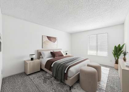 A bedroom with a large bed and a small table with a plant on it.