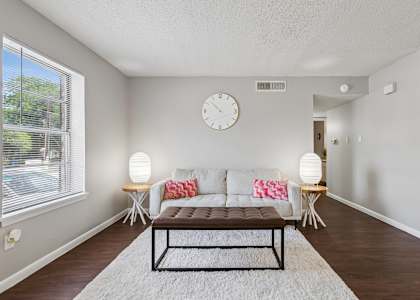 A living room with a couch, a table, and a clock on the wall.