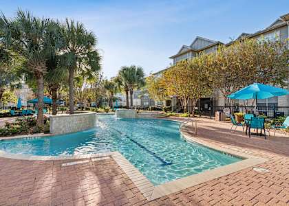 A swimming pool surrounded by palm trees and lounge chairs.