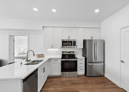 A modern kitchen with white cabinets and stainless steel appliances.