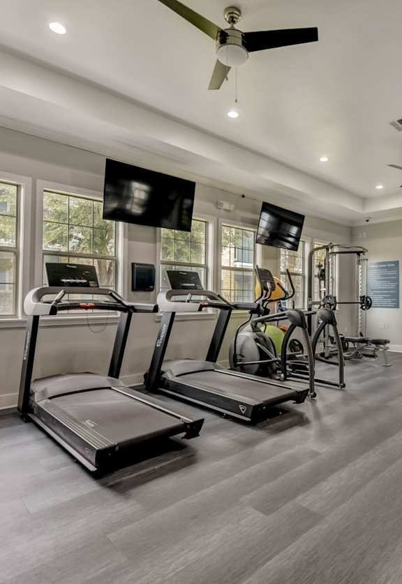 A spacious gym with treadmills, elliptical machines, and a television.