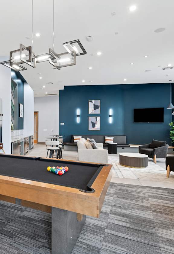 A pool table is in the middle of a room with a grey carpet.