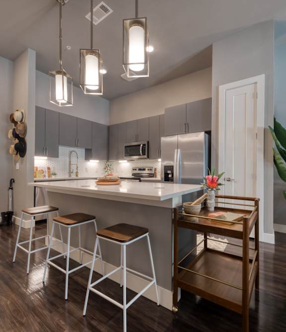 A kitchen with white countertops and grey cabinets.