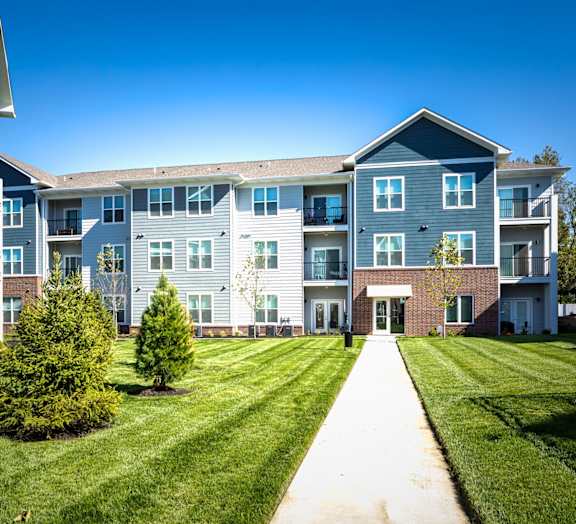 an exterior view of an apartment building with grass and trees