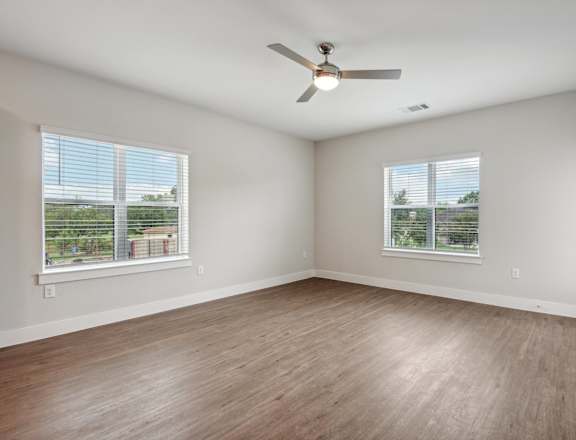 an empty living room with wood floors and a ceiling fan at The Virginia, Seguin, 78155