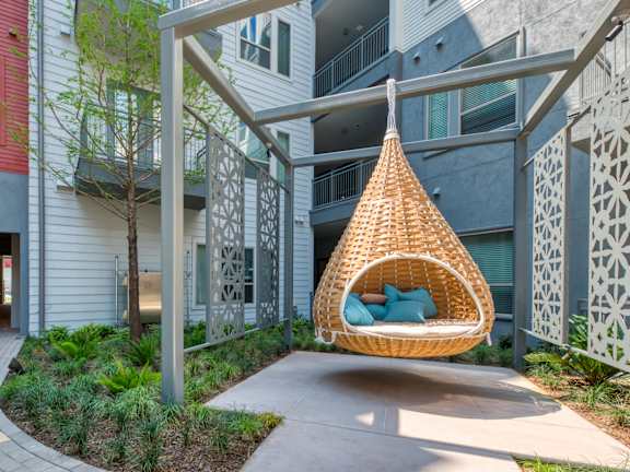 A patio with a couch, chairs, and a table with a tree in the background.
