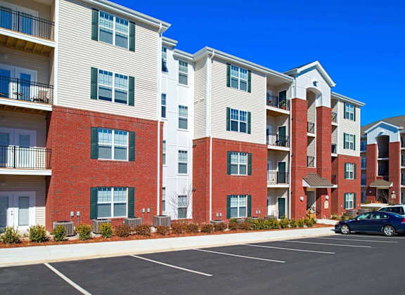 A row of apartment buildings with a car parked in the parking lot.