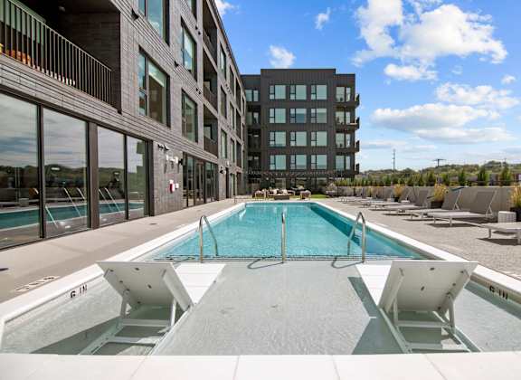 a swimming pool with lounge chairs in front of a building