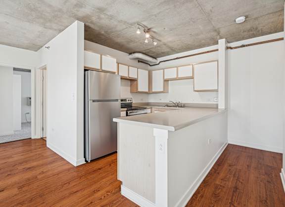 A kitchen with white cabinets and a stainless steel refrigerator.