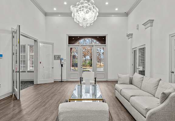 A modern living room with a glass coffee table and a grey sofa.