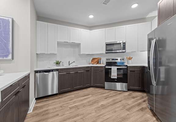 A modern kitchen with wooden floors and stainless steel appliances.