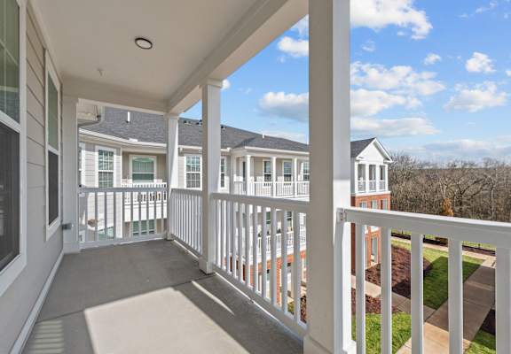 A balcony with white railings and a view of a residential area.
