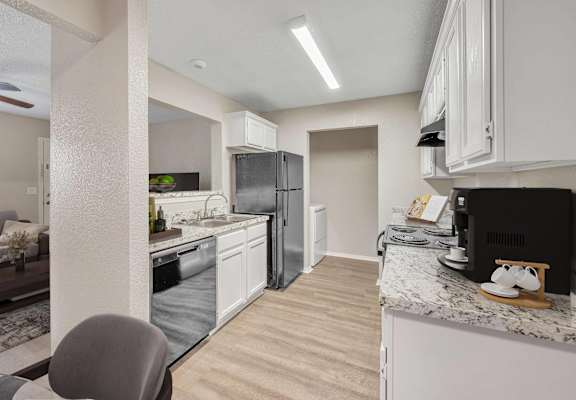 A kitchen with white cabinets and a black countertop.