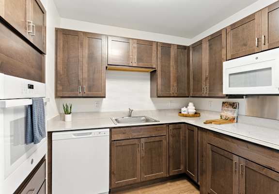 A kitchen with brown cabinets and white appliances.