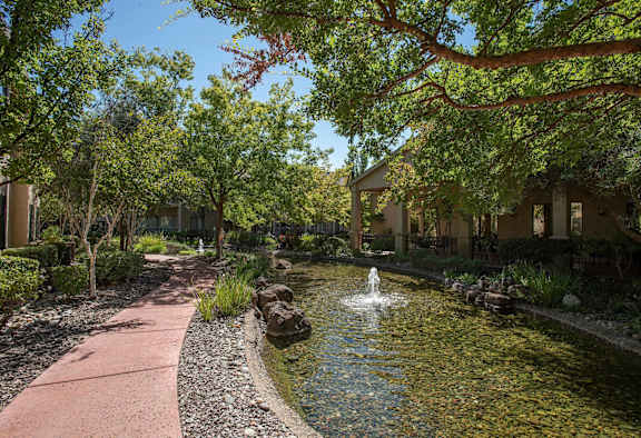 a fountain in the middle of a pond in front of a building at Winding Commons Senior Living, Carmichael, CA, 95608