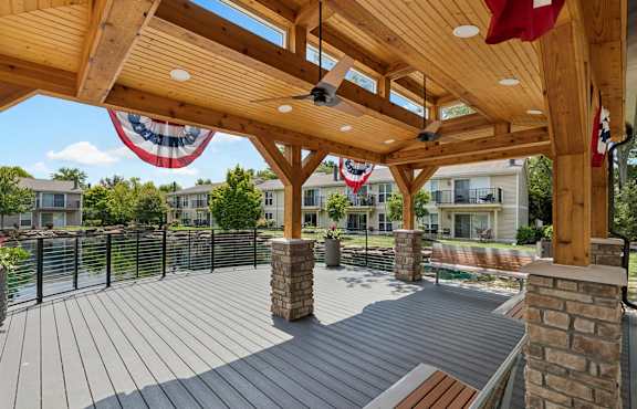 A wooden deck with a ceiling fan and a red, white and blue banner.
