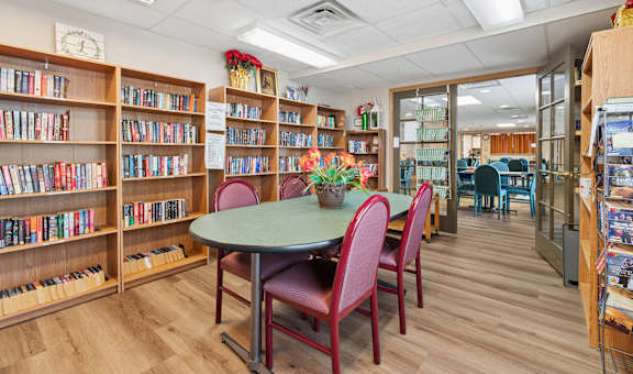 A library with a table and chairs and bookshelves.