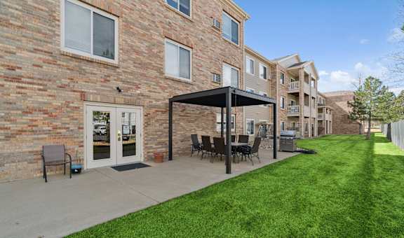 A patio with a table and chairs is in front of a brick building.