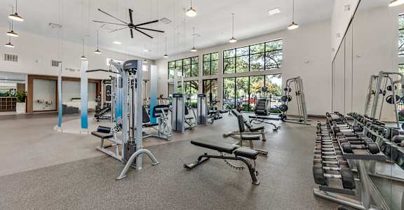 A spacious gym with a variety of equipment and a ceiling fan.