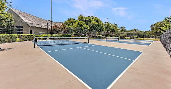 A tennis court surrounded by a fence and trees.