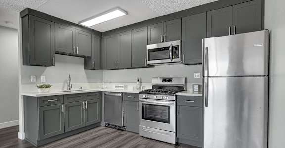a kitchen with gray cabinets and stainless steel appliances