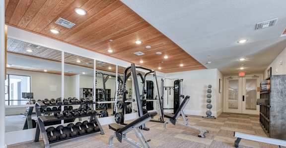a gym with weights and a lot of mirrors on the wall