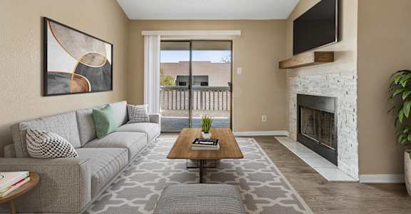 A living room with a grey couch, a coffee table, a fireplace, and a painting on the wall.
