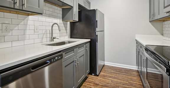 an empty kitchen with stainless steel appliances and white cabinets
