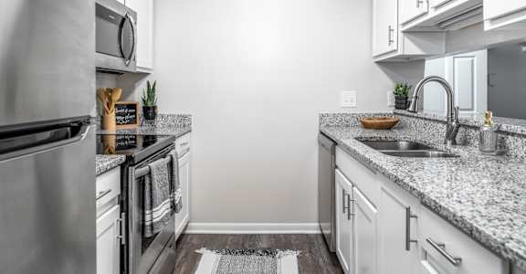 A modern kitchen with a granite countertop and stainless steel appliances.