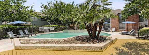 A pool surrounded by a wooden deck and trees.