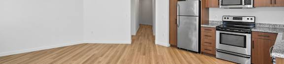 an empty kitchen with wood flooring and stainless steel appliances