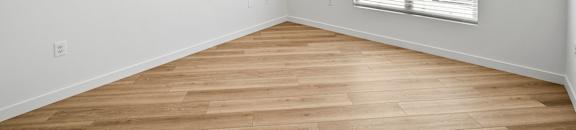 the living room of an empty home with wood flooring and a ceiling fan