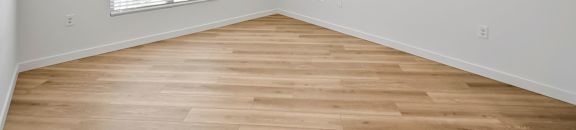 an empty room with wood flooring and a ceiling fan