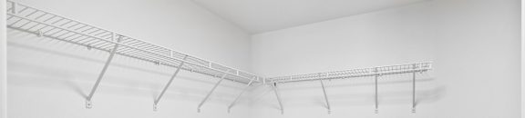 an empty room with white walls and a wire rack on the wall