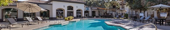 A sunny day at the poolside with a table and chairs.