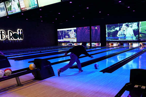 A man is bowling in a B-Roll Bowling alley.