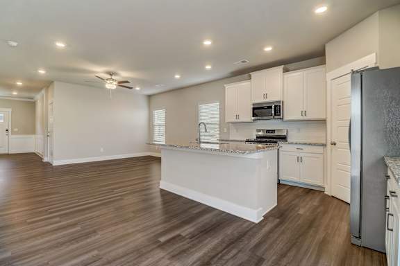 A kitchen with a white island and wooden floors.
