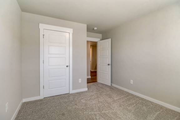 A room with a carpeted floor and two white doors.